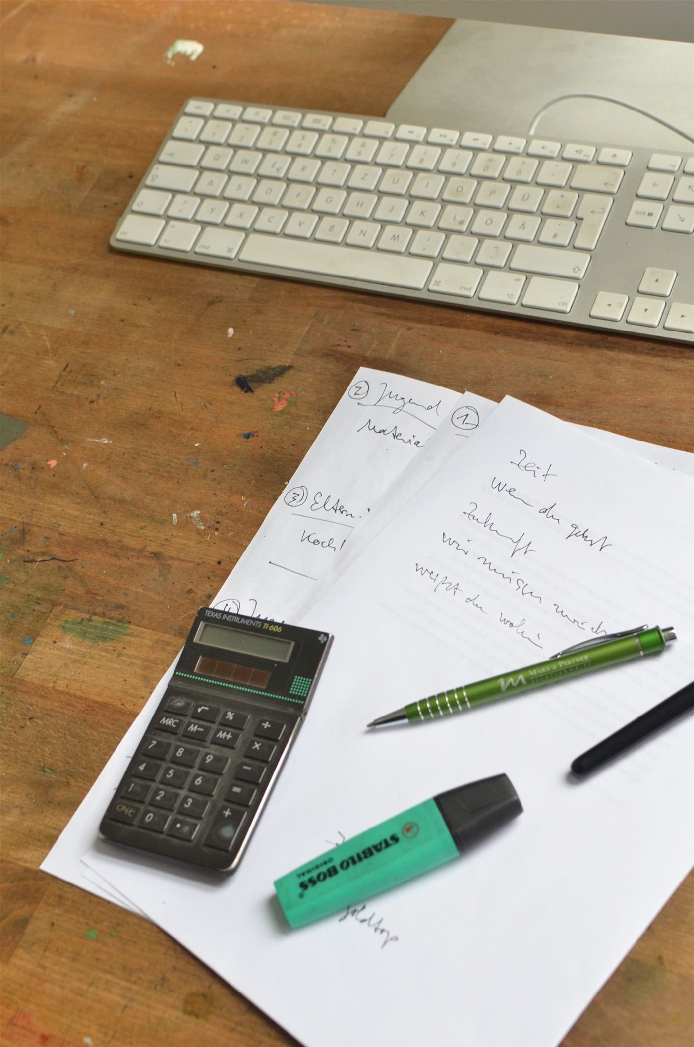 A desk with handwritten notes, a calculator and a keyboard