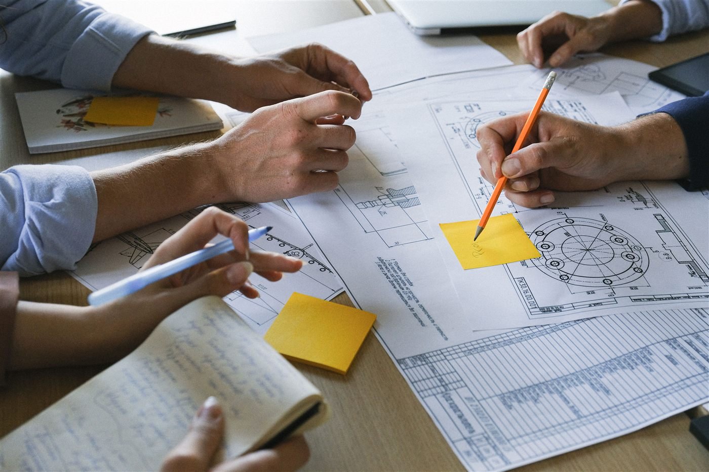 Hands sketching technical drawings with sticky notes on the table