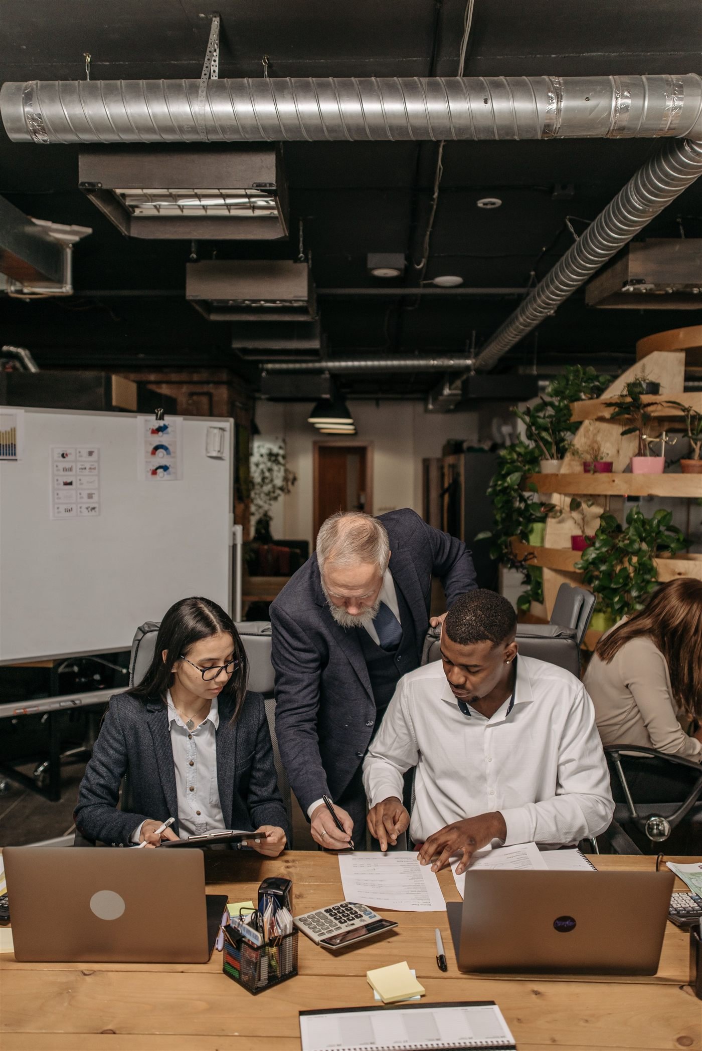 A team working together at shared desks while a colleague guides them
